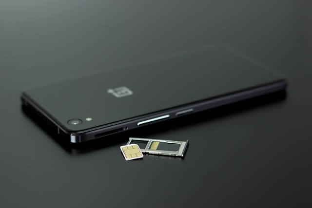 Black smartphone with an open sim port, sim case and a sim card
